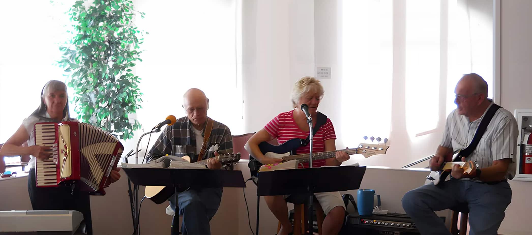 Four musicians performing with various instruments indoors.