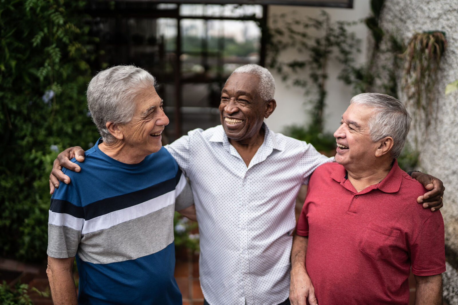 Three smiling elderly men enjoying a moment together.
