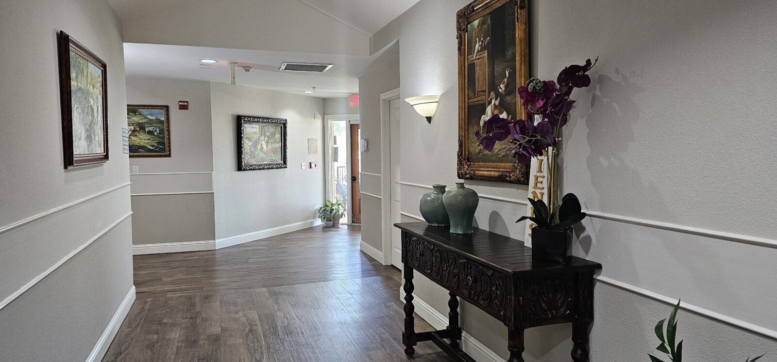 Elegant hallway with artwork and decorative plants.