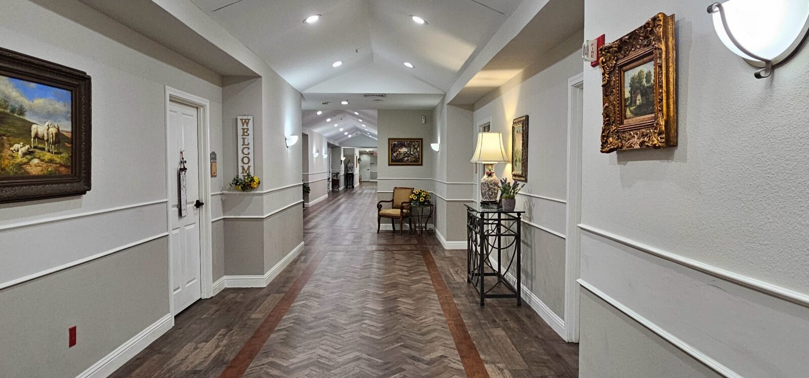 Bright hallway with art, welcoming decor, and wooden flooring.