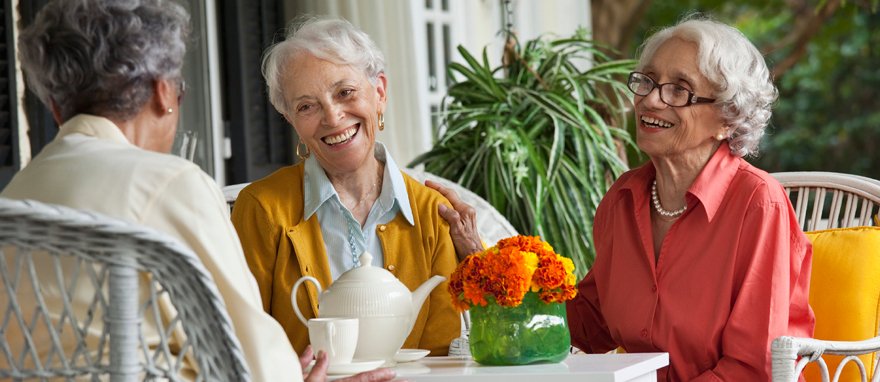 Three elderly women enjoying time together on a porch.