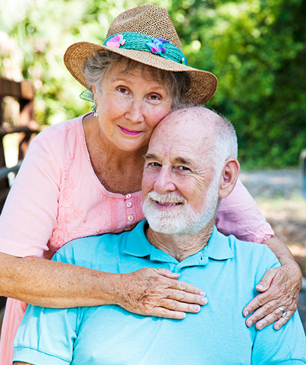 Elderly couple smiling, enjoying time together outdoors.
