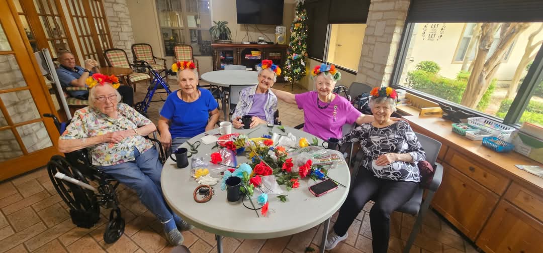 Seniors enjoying crafts with colorful floral headbands.