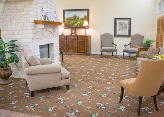 Cozy room with fireplace, chairs, and floral carpet.